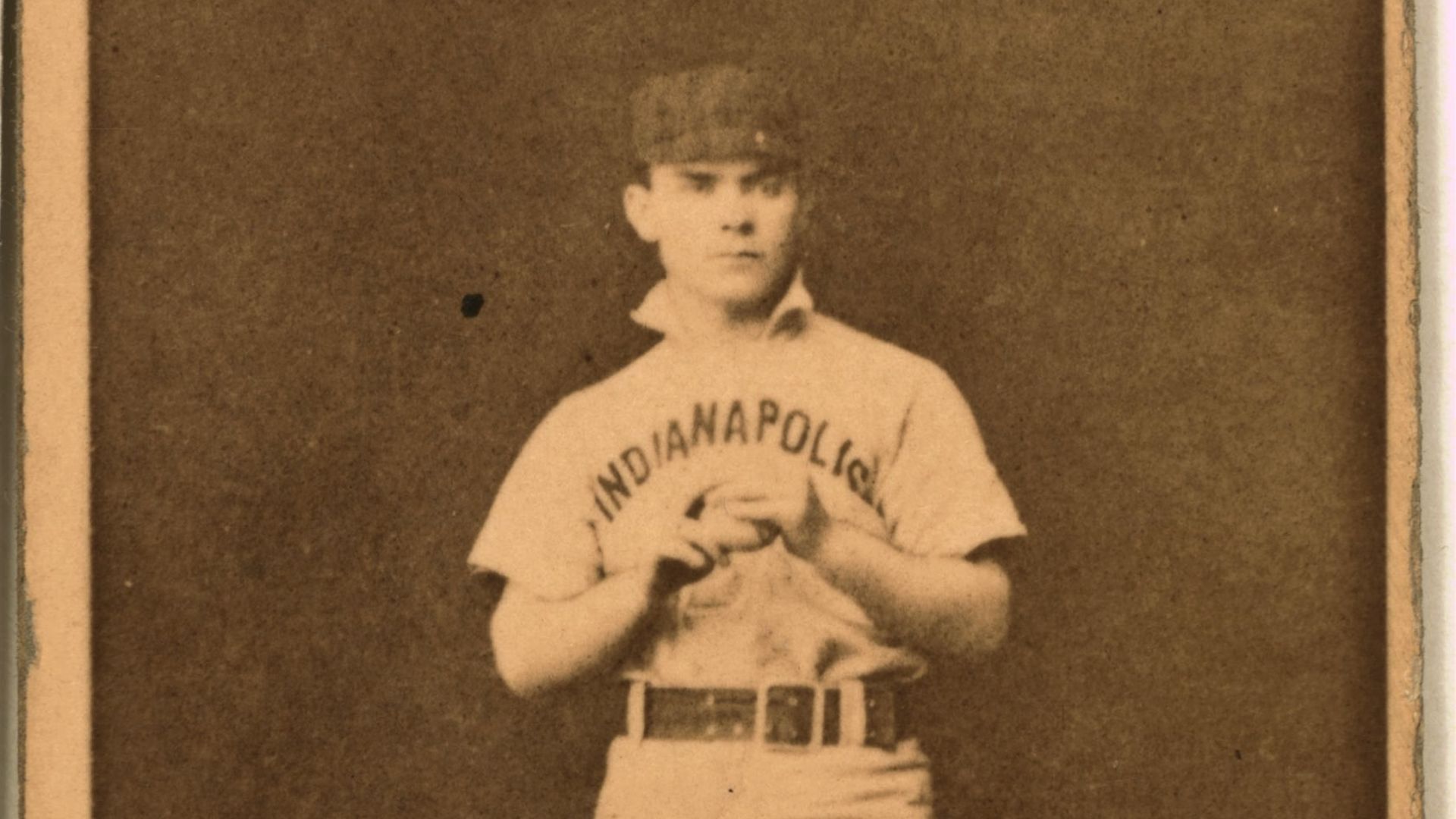 A baseball player holding a baseball ball with two hands.