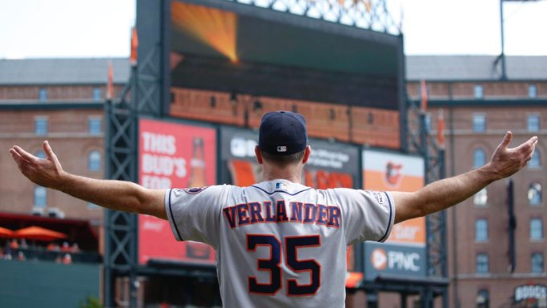 Justin Verlander showing his jersey on the camera with his arms wide open.