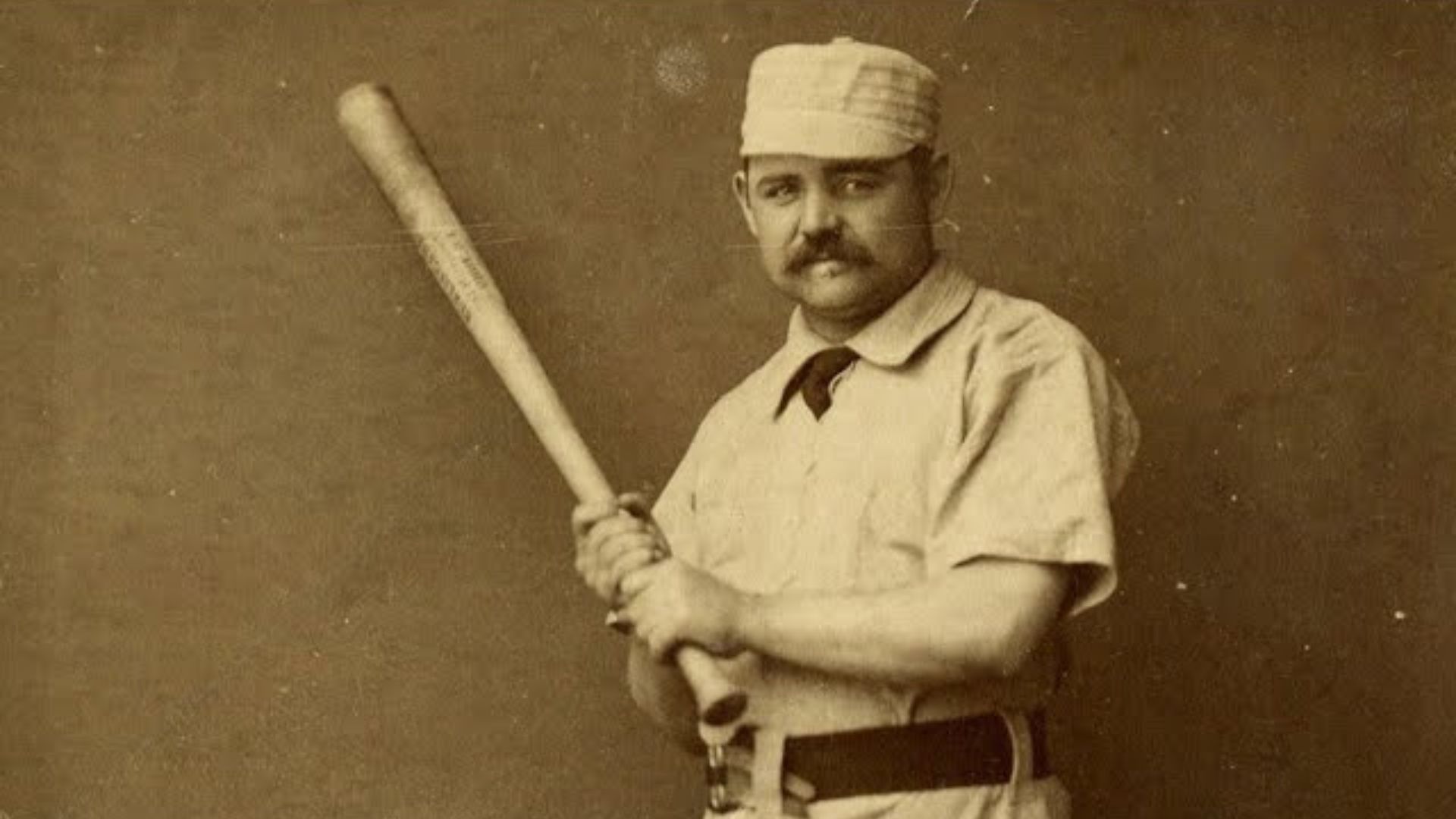 Pud Galvin holding a baseball bat while posing for the camera.