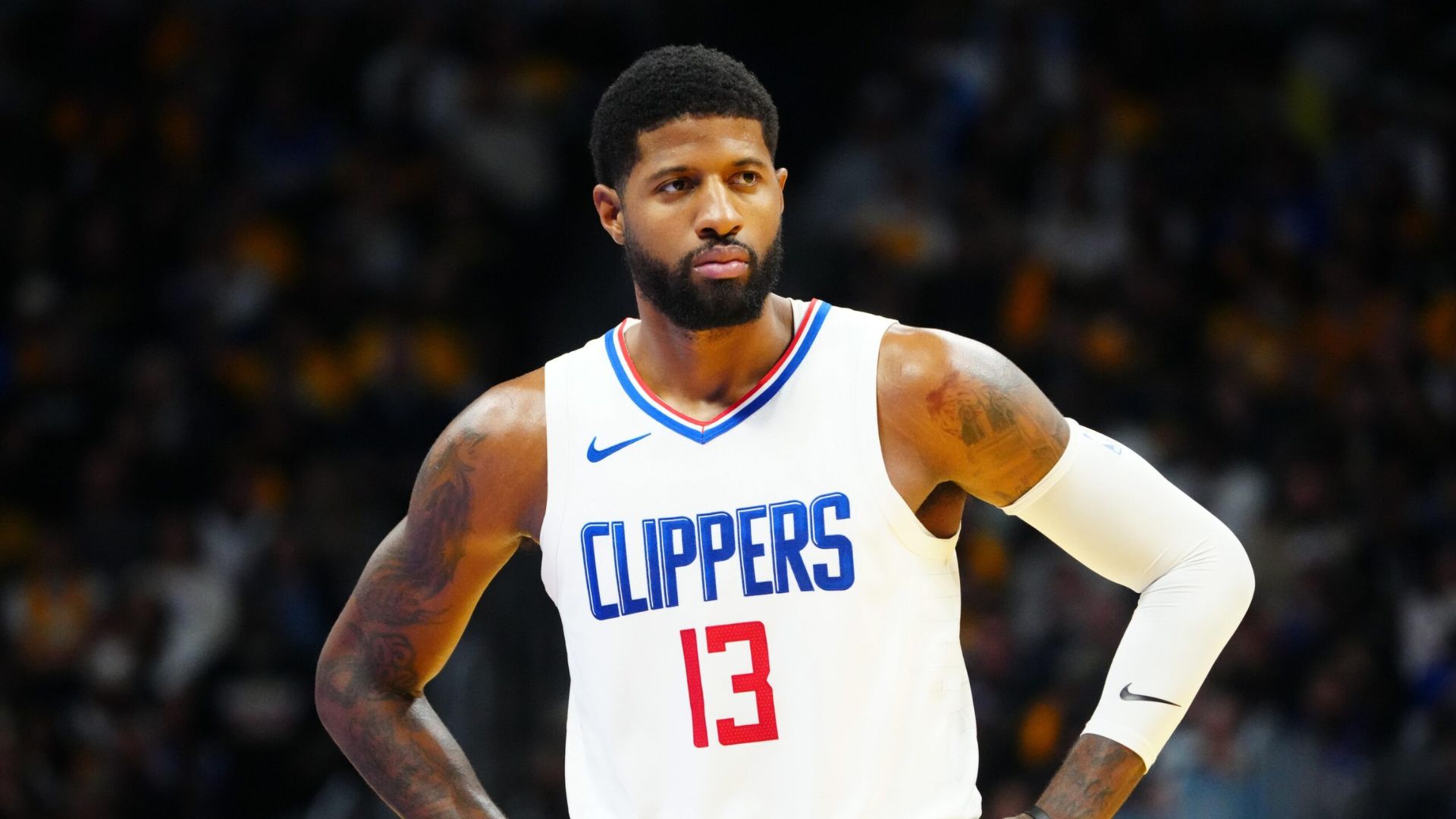 Paul George standing on the court with his hands on his waist.