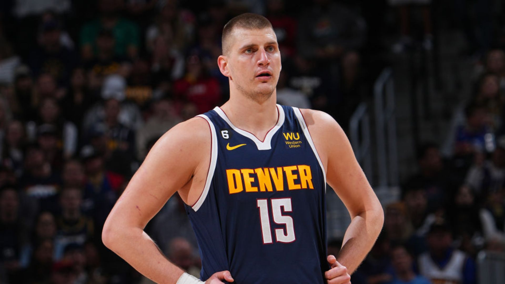 Nikola Jokic standing on the court with his hands on his waist.