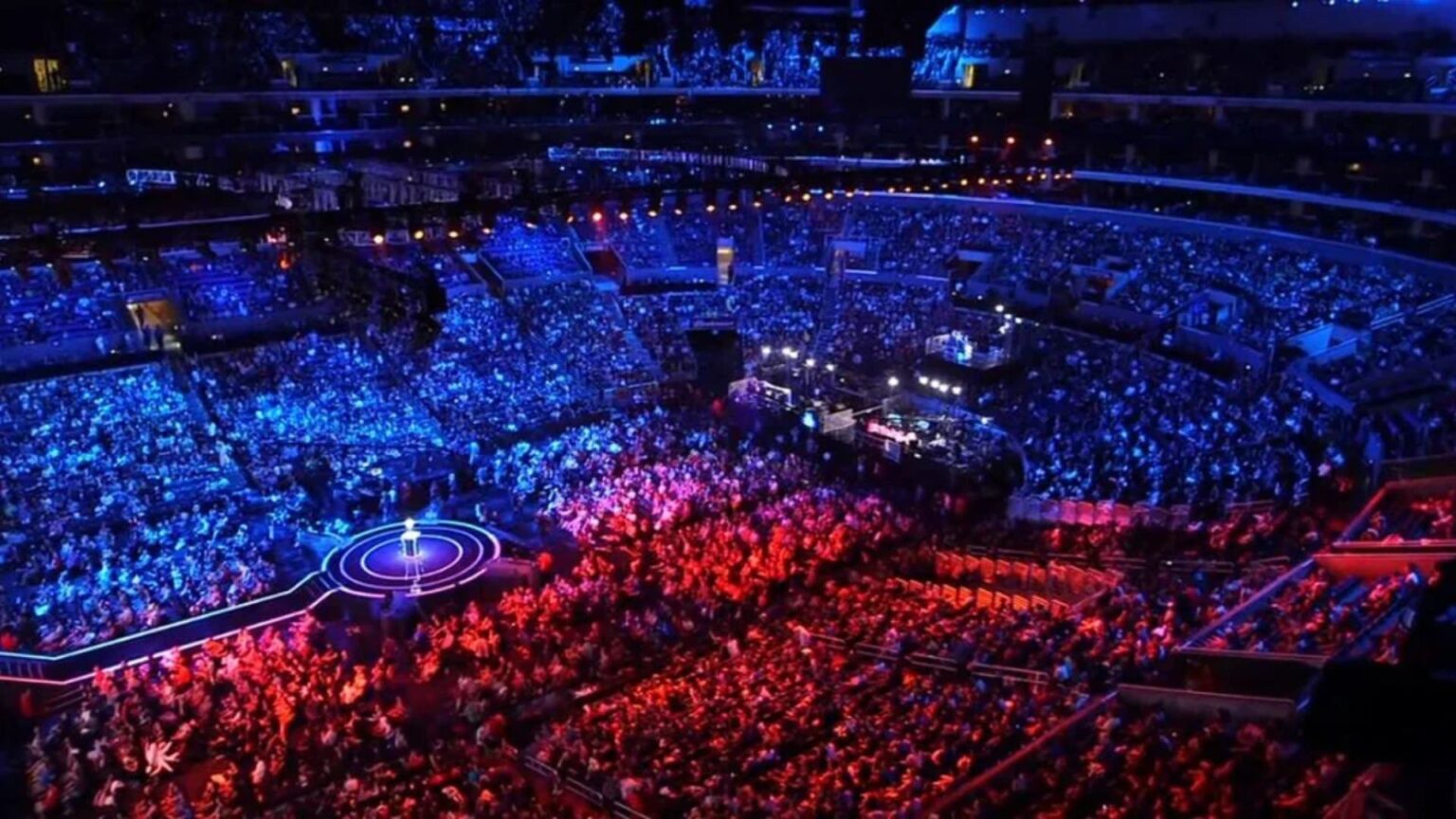 A light of blue and red illuminates the crowd who is looking on the stage.